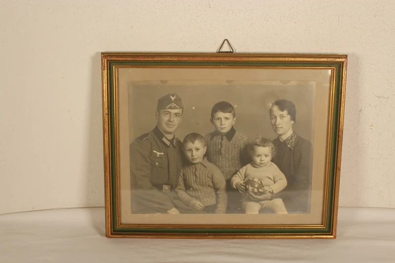 Studioaufnahme in einem Vintage-Rahmen, die einen Wehrmachtssoldaten mit seiner Familie zeigt.