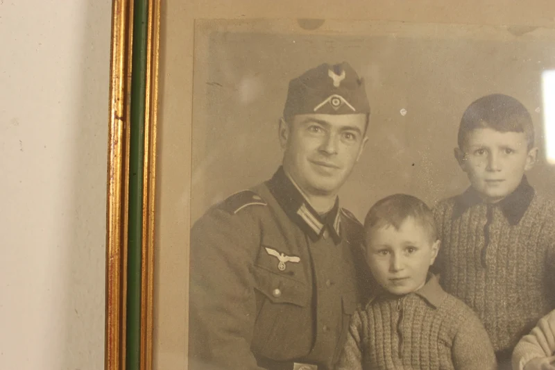 Studioaufnahme in einem Vintage-Rahmen, die einen Wehrmachtssoldaten mit seiner Familie zeigt.
